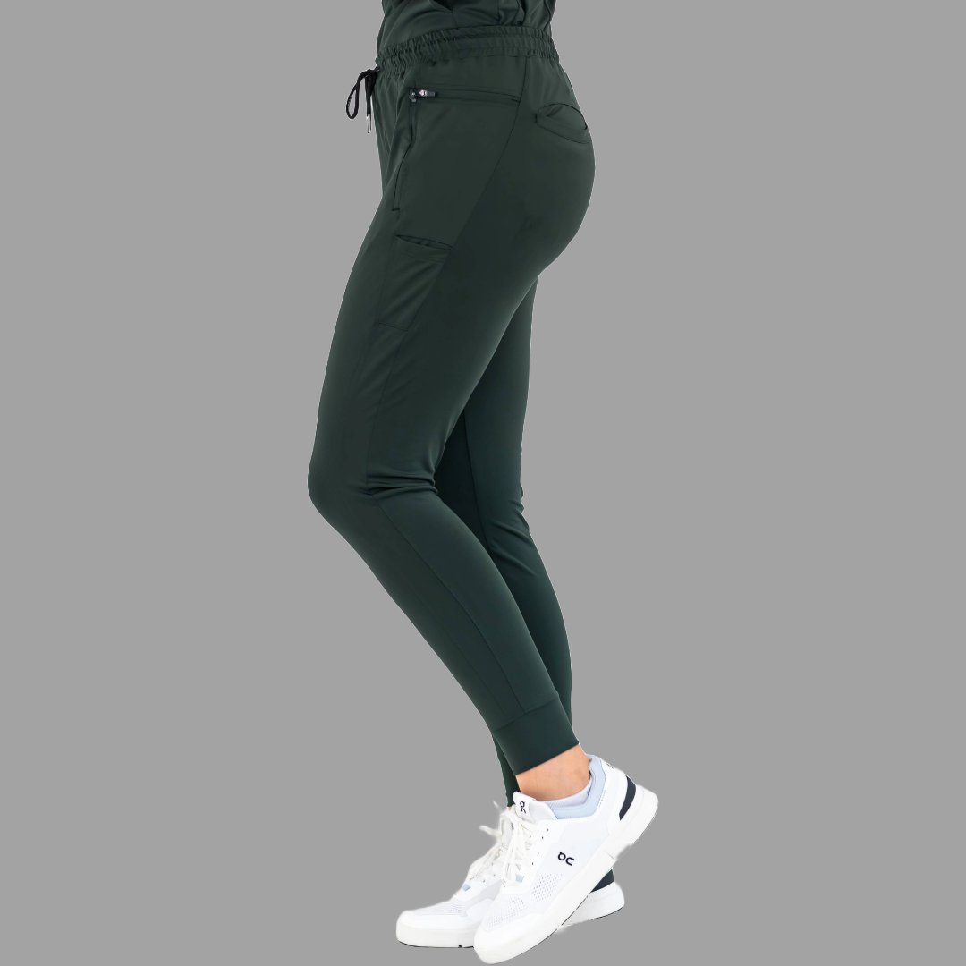Three-quarter back view of women's scrub joggers 920 super stretch bottle green in a relaxed stance.